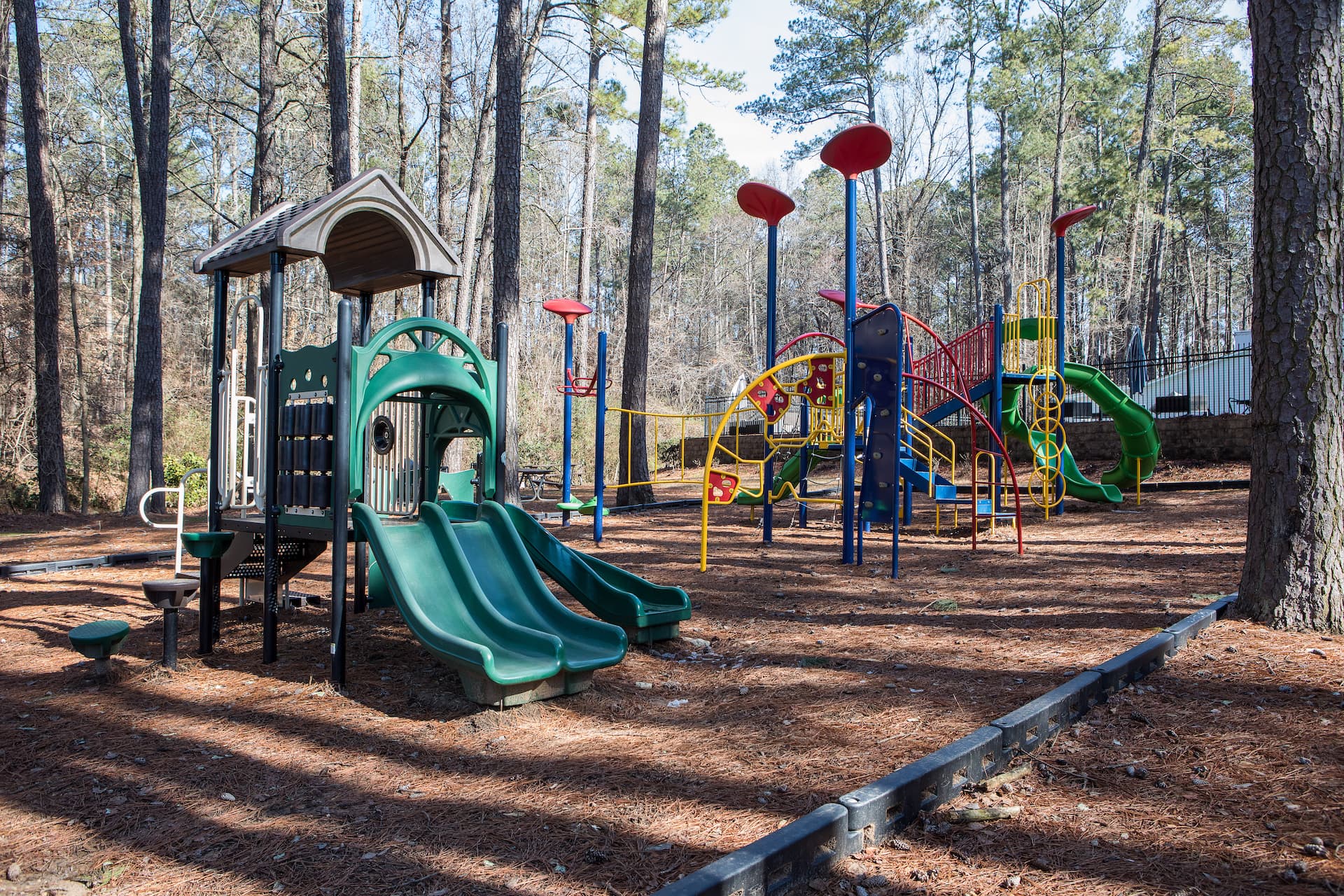 Playground set in wooded area with pine straw