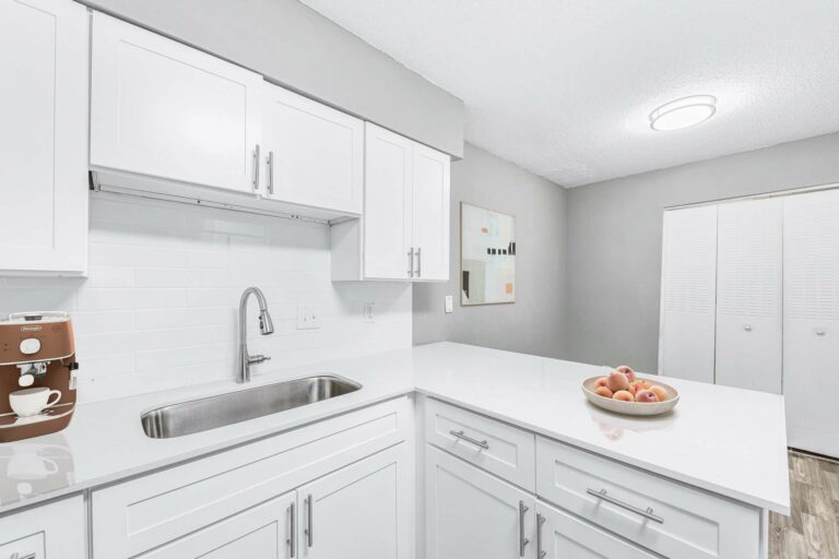 Gooseneck faucet and white quartz counters in kitchen