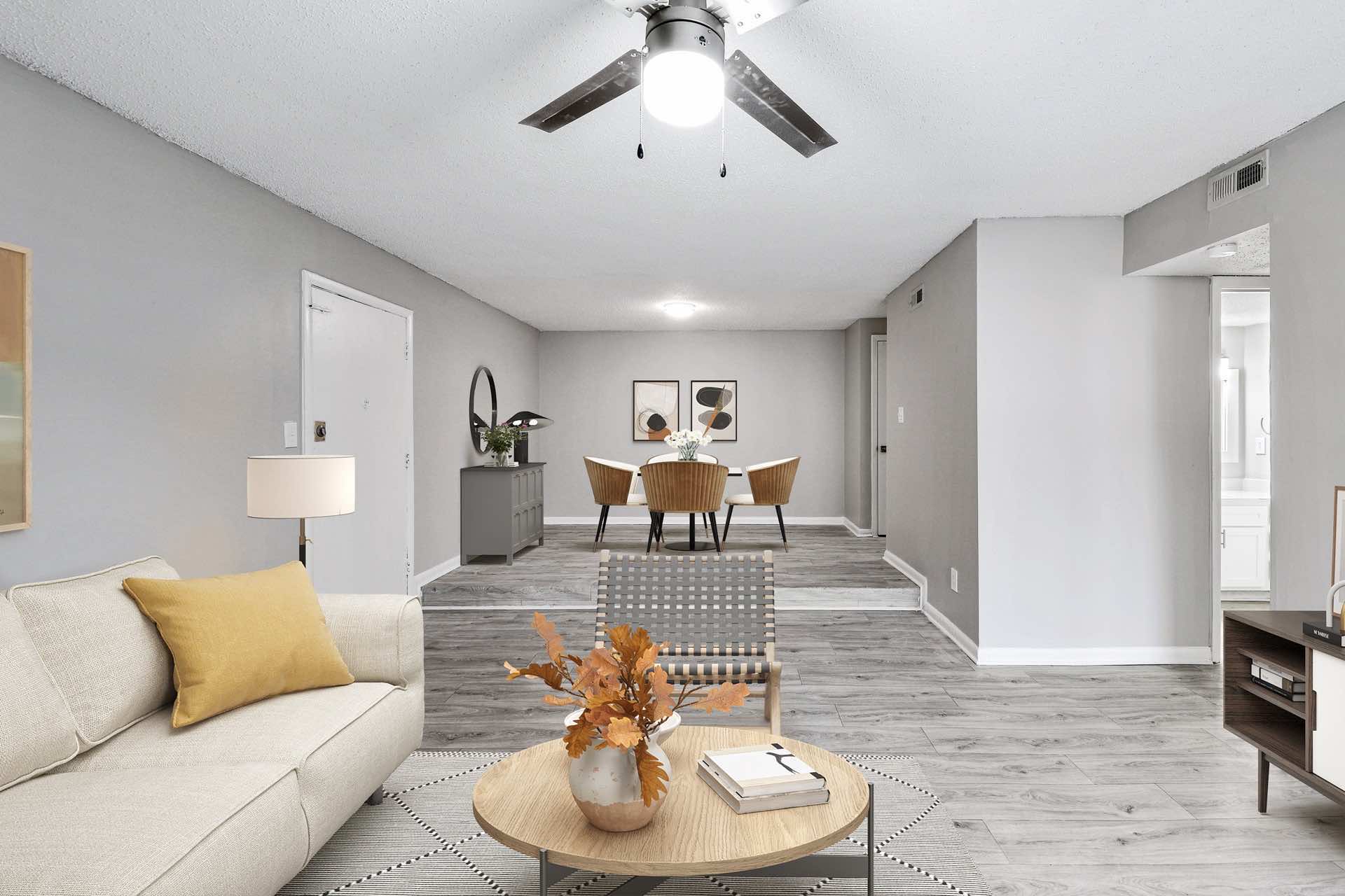 apartment open floor layout showing living room with ceiling fan and dining room in background
